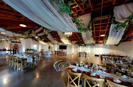 Elegant banquet hall with draped white fabric, wooden ceiling beams, and tables set for a formal event