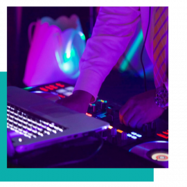 DJ hands adjusting controls on a mixer with purple-blue lighting and a laptop nearby