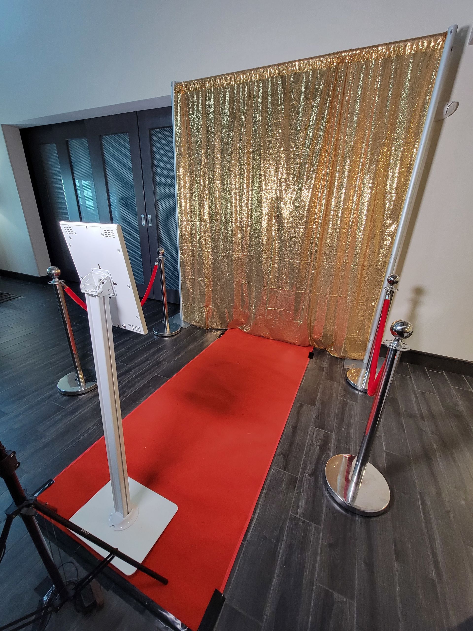 Red carpet photo backdrop with gold curtain and stanchions in a hallway.