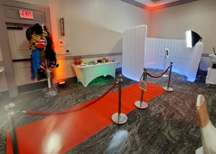 Red carpet event entrance with stanchions, white partitions, and a decorated table in a hallway