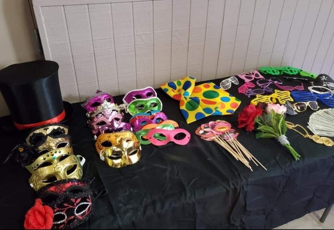 Table covered with colorful masquerade masks and props, including gold, pink, black, and floral designs.