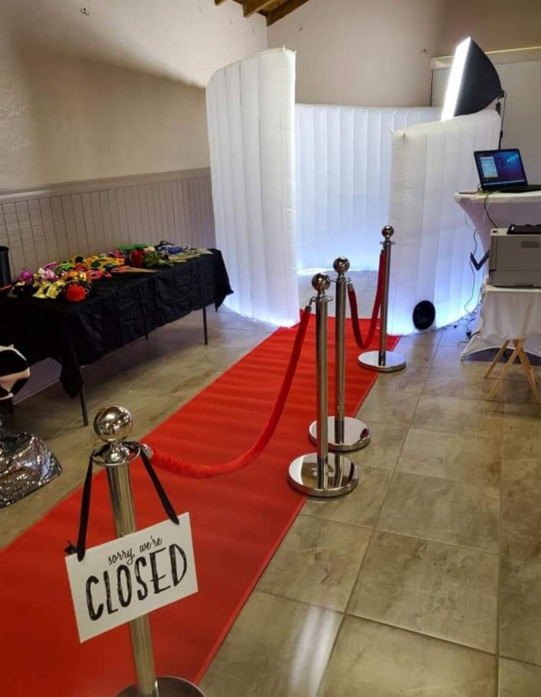 Closed event area with red carpet, stanchions, white backdrop, and a table of refreshments.