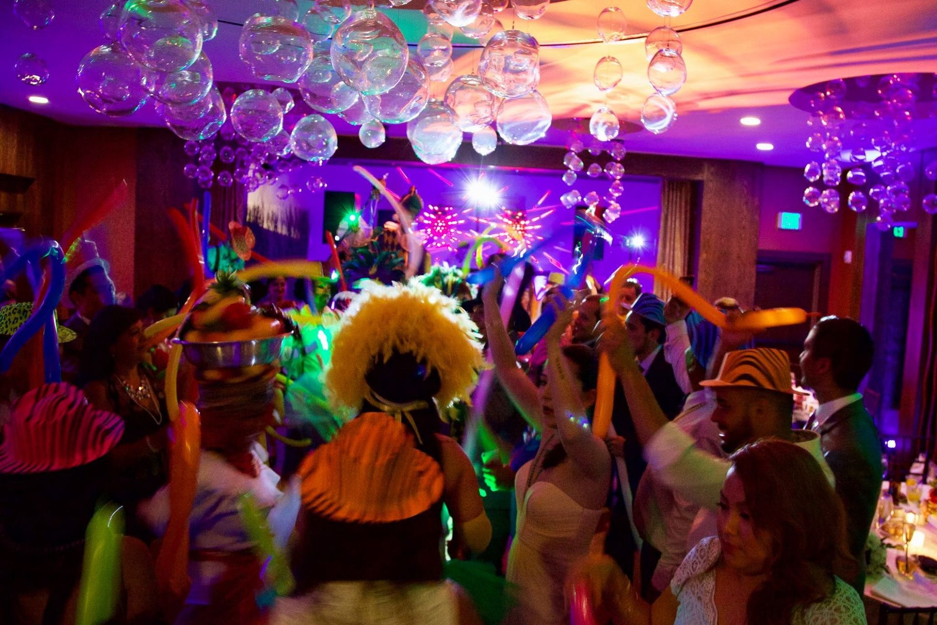 Colorful party crowd dancing under disco lights and balloons in a decorated room