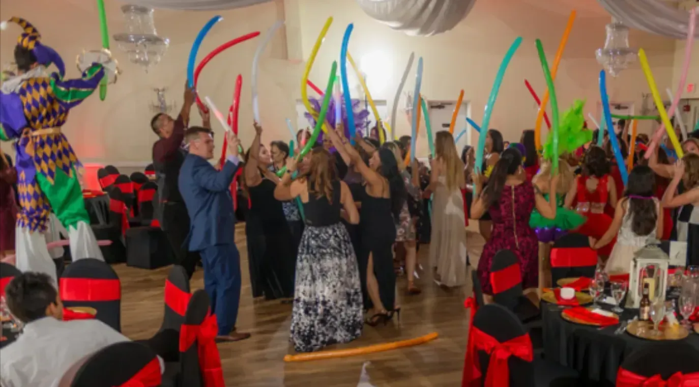 People dancing indoors with colorful ribbons raised during a festive celebration