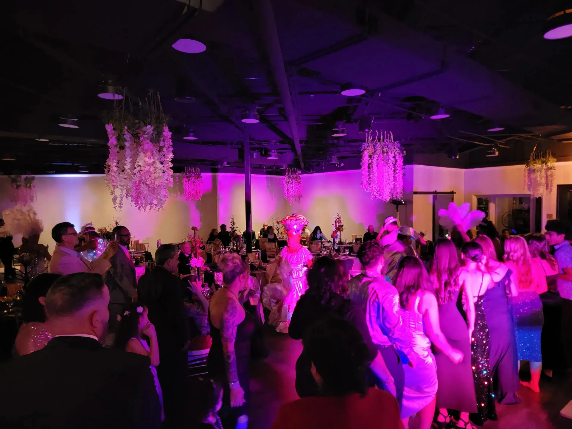 People dancing at a dimly lit party with purple lighting and chandeliers