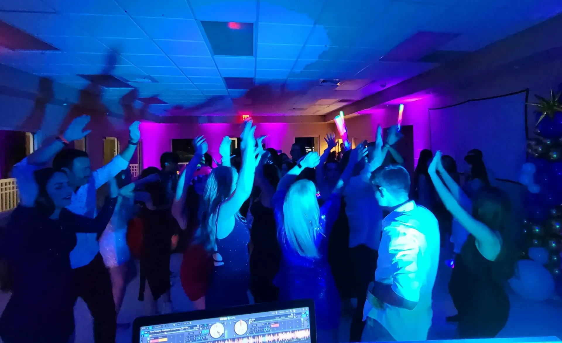 Crowd dancing at a party under blue and purple stage lights