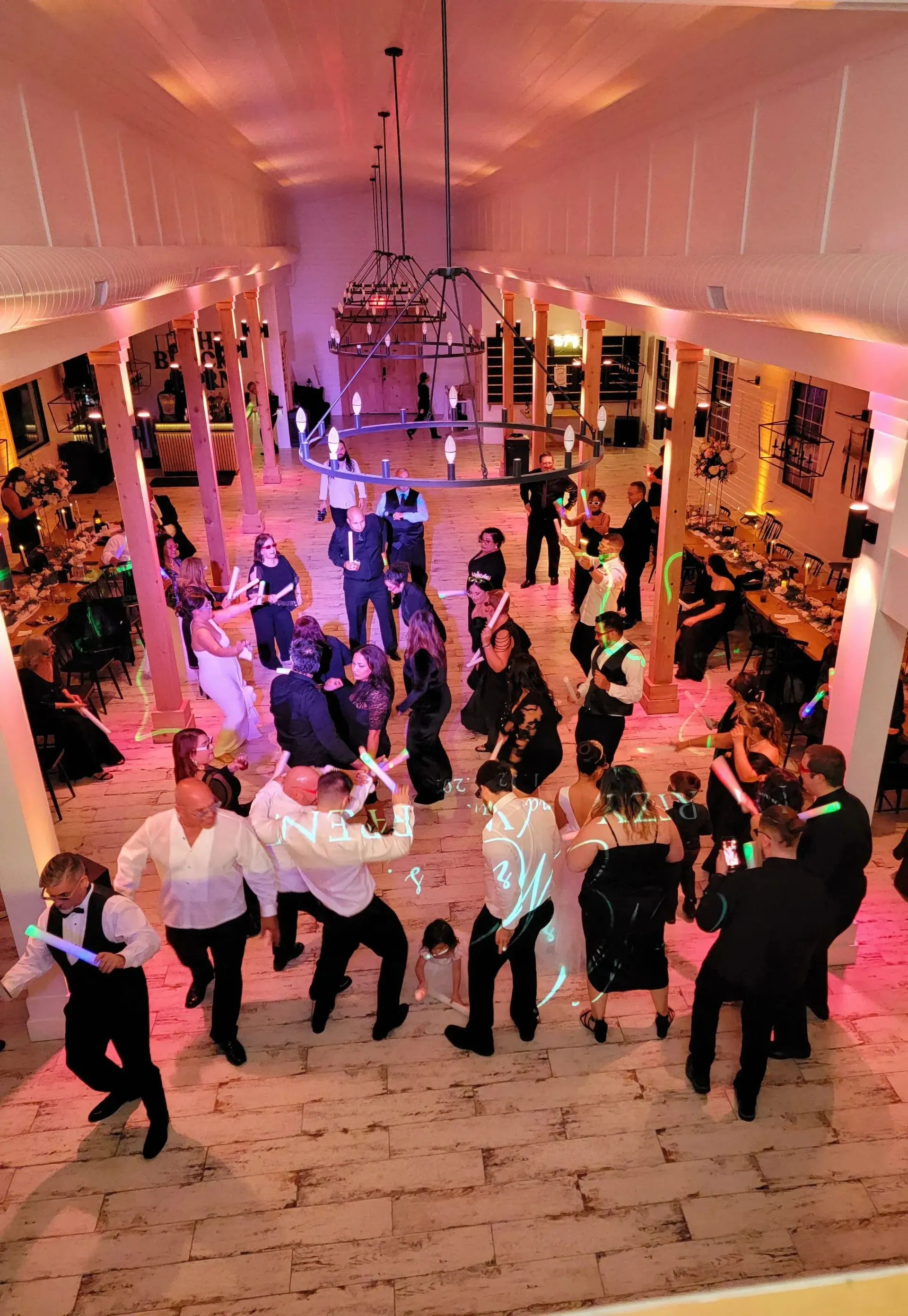 People dancing at a lively indoor party with pink and purple lighting, viewed from above