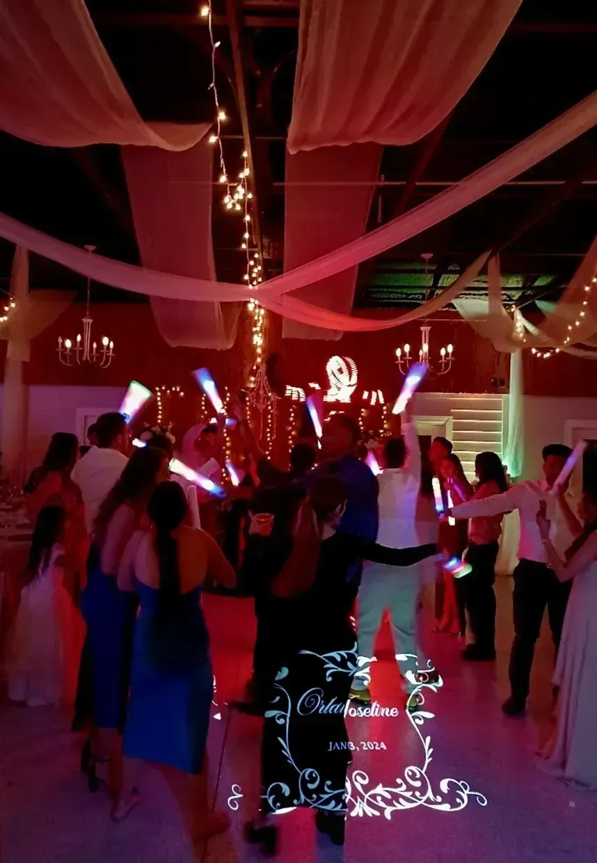 Guests dancing under pink draped lights at a decorated indoor event
