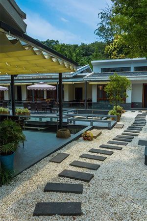 Pathway of stepping stones Pathway of stepping stones leads to a building with a yellow awning and patio seating, surrounded by a white gravel yard.