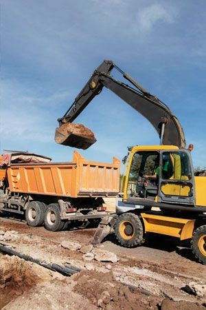 Yellow excavator Yellow excavator loading an orange dump truck with dirt at a construction site under a blue sky.