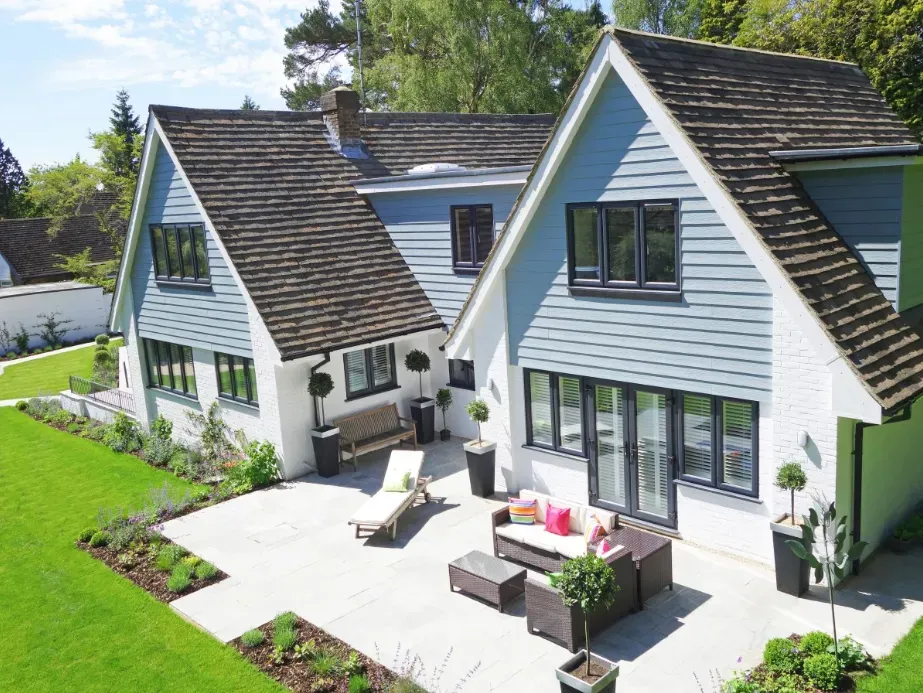 House with blue siding, patio furniture, and a green lawn.