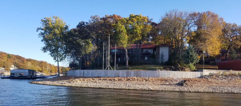 A house is sitting on a small island in the middle of a lake surrounded by trees.