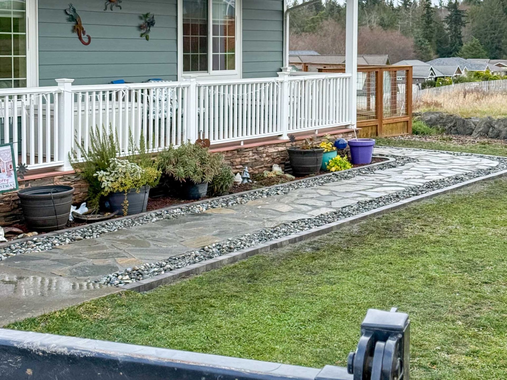 Exterior view of house with porch, a stone pathway, and greenery.
