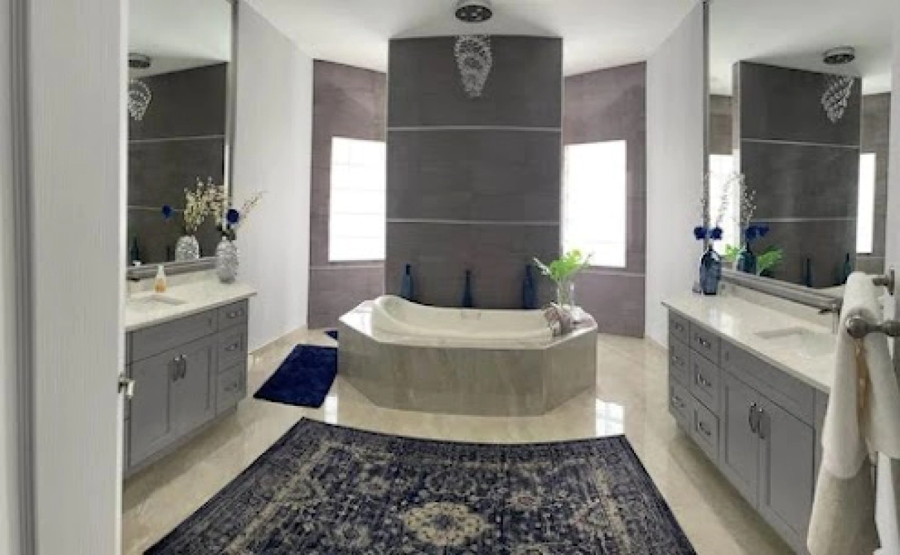 Elegant bathroom with a central bathtub, gray cabinets, and marble flooring.
