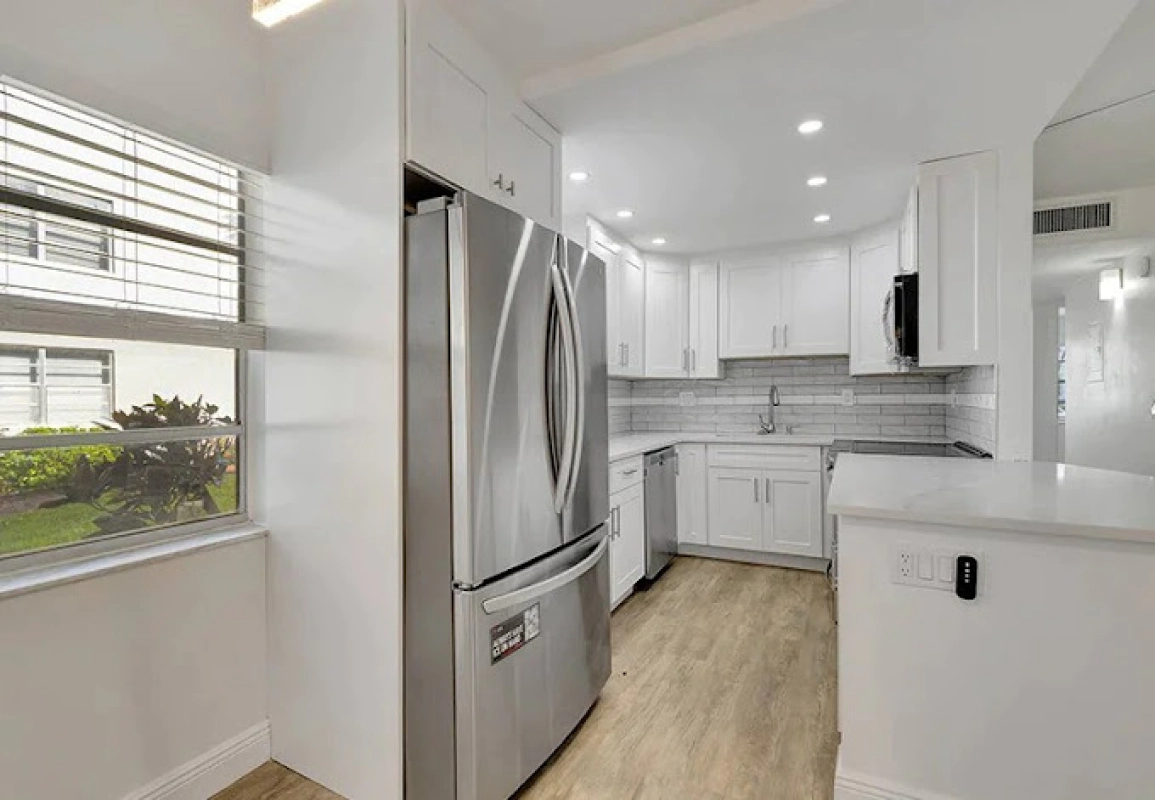 Bright, white kitchen with stainless steel appliances and light wood flooring.