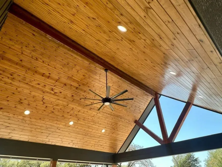 Wood-paneled vaulted ceiling with recessed lights and a large black ceiling fan.