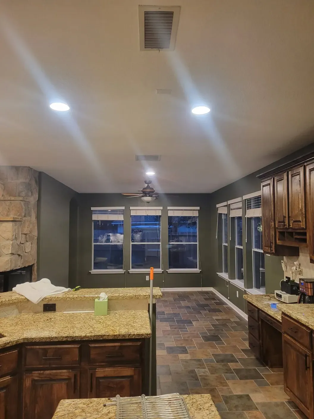 Modern kitchen with granite island, dark wood cabinets, tiled floor, and recessed ceiling lights.