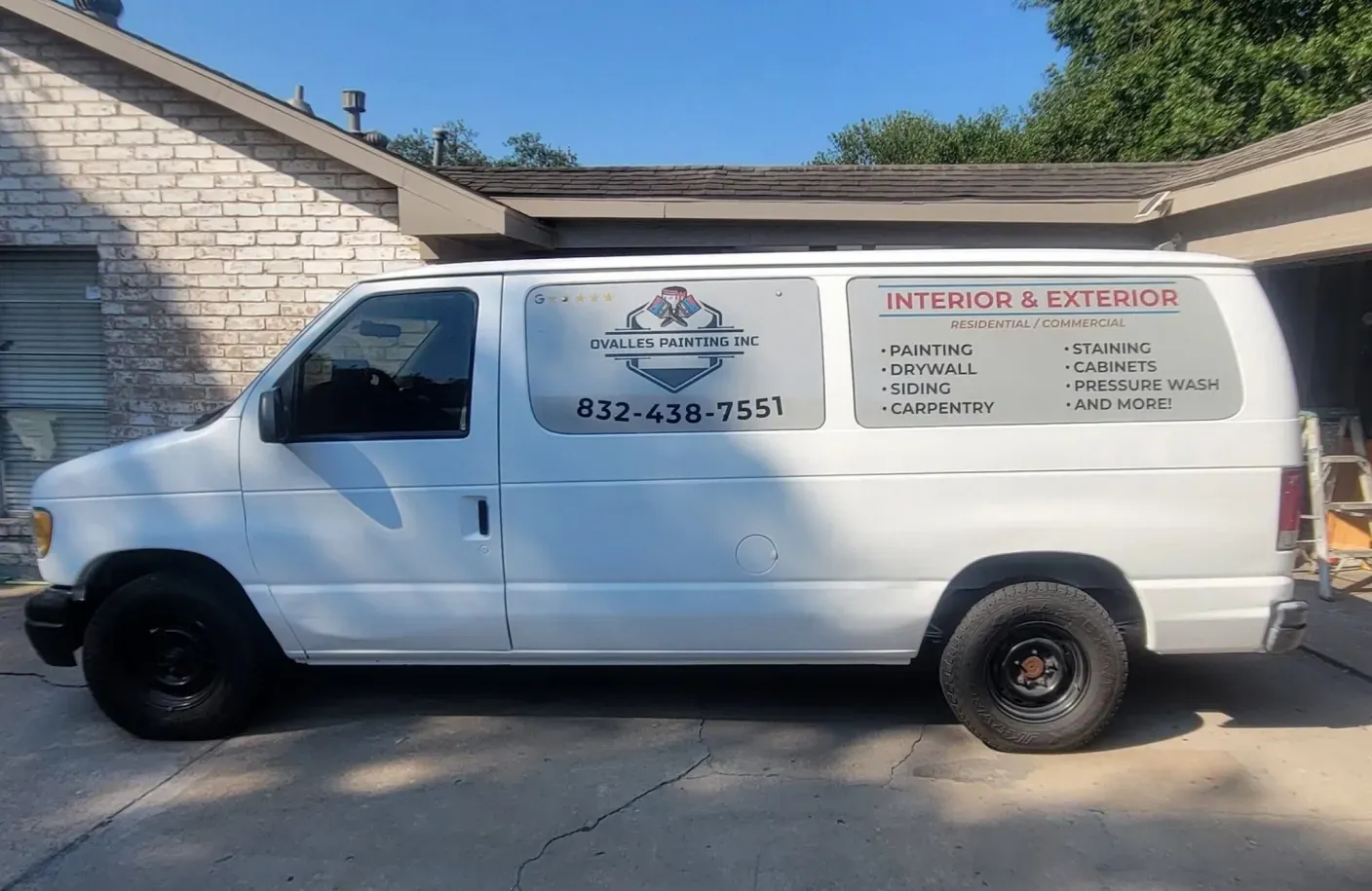 White work van with business signage parked beside a brick house in a driveway