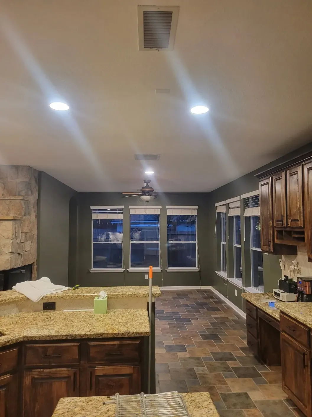 Modern kitchen with dark wood cabinets, granite island, stone backsplash, and recessed lighting