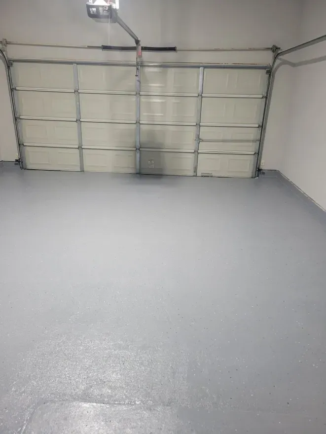 Empty garage with a closed sectional door and light gray floor.