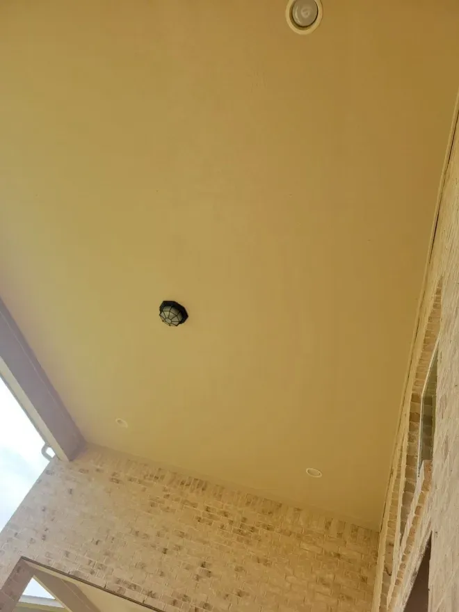 Ceiling and upper wall of a tiled porch, with a light fixture and a skylight opening.