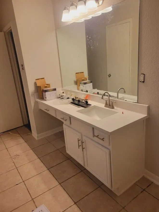 Bathroom vanity with large mirror, double sink, white cabinets, and tiled floor