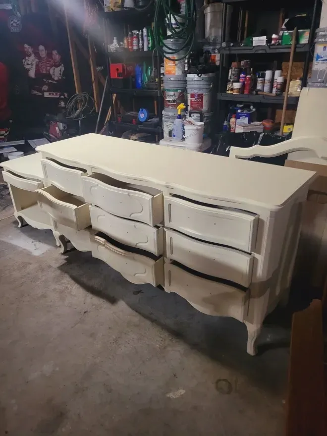 White painted dresser with drawers in a cluttered garage or workshop.