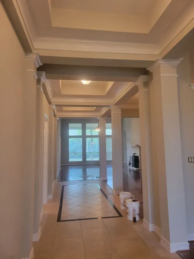Long hallway with tiled floor, white columns, and glass doors at the far end.