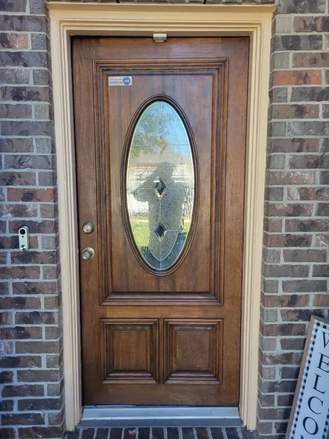 Wooden front door with oval glass insert set in a brick exterior wall