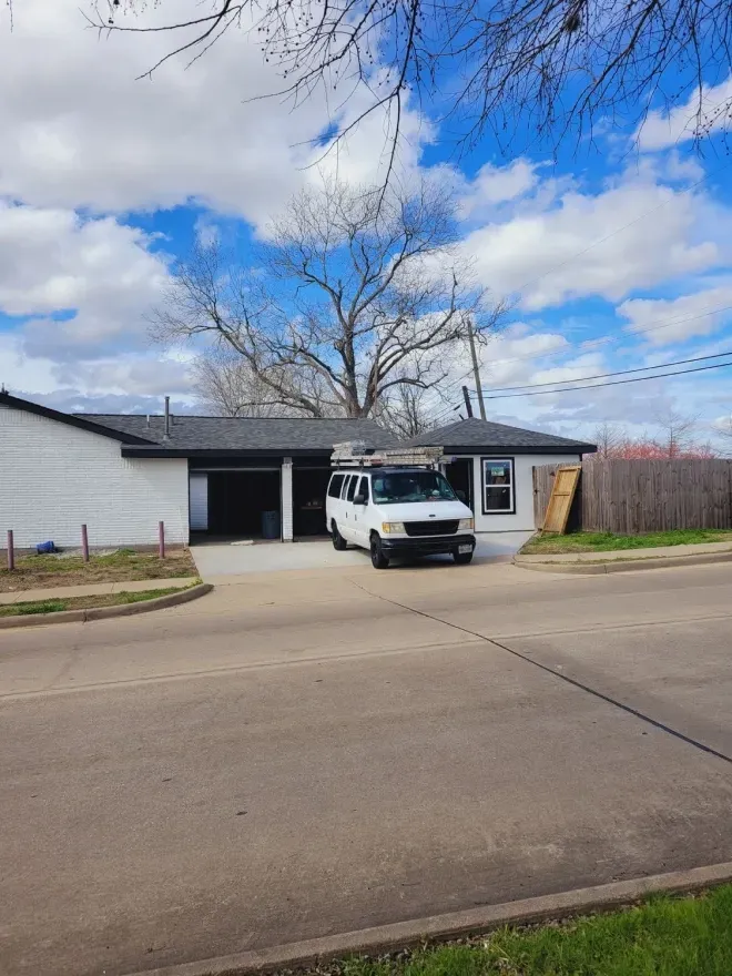 White van parked in front of a single-story house on a quiet suburban street under a cloudy blue sky