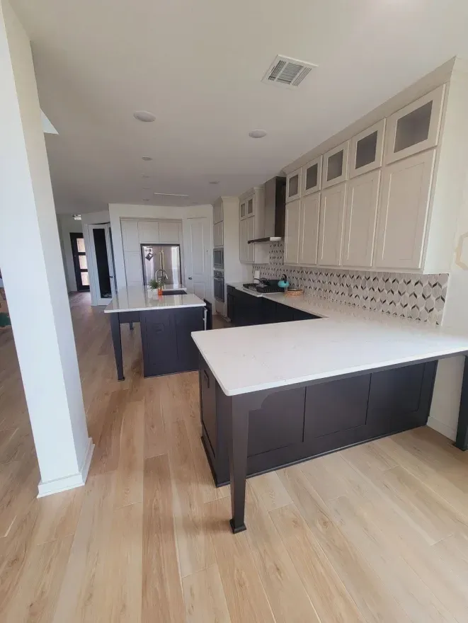 Bright modern kitchen with white countertops, dark cabinets, and light wood flooring