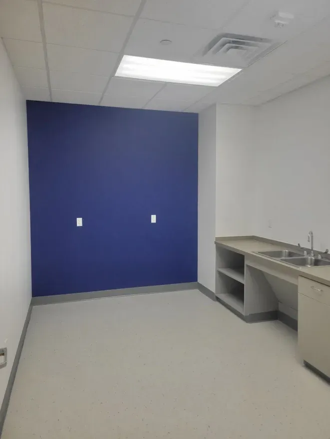 Empty office kitchenette with blue accent wall, sink, and countertops