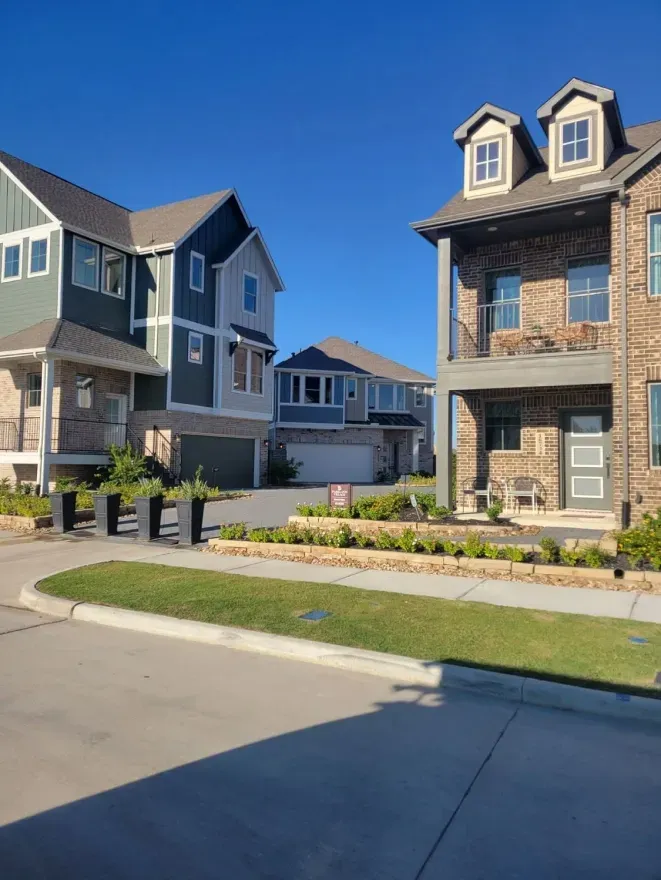 Modern suburban townhomes with landscaped front yards on a sunny day