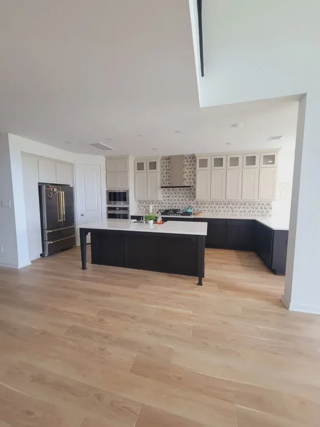 Bright, modern kitchen with black island, white cabinets, and light wood floors