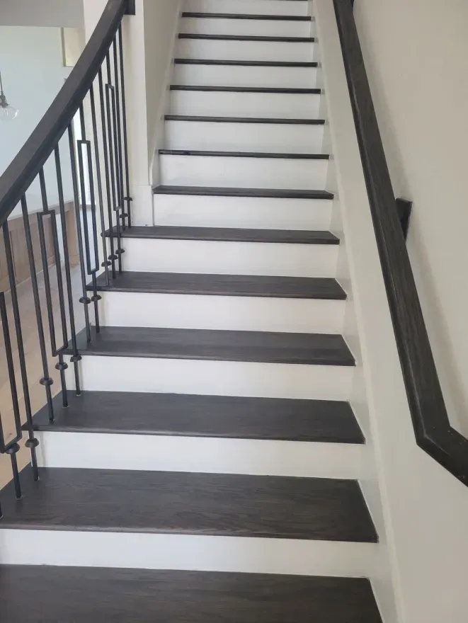 Indoor staircase with dark railings and white steps against beige walls