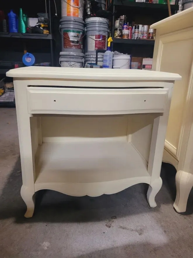 Cream-painted vintage nightstand with drawer and shelf in a garage or workshop setting.