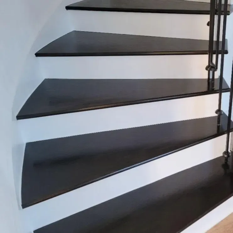 Modern black floating staircase steps against a white wall