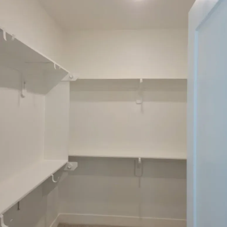 Empty white walk-in closet with built-in shelves and hanging rods
