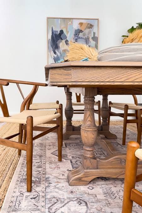 Wooden dining table with chairs on a patterned rug in a bright room