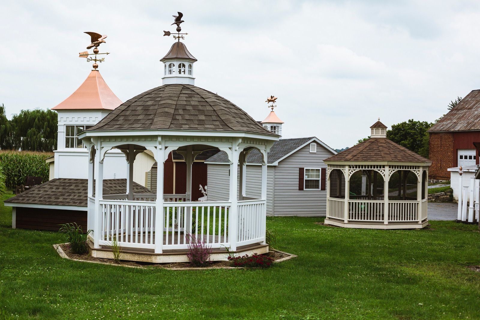 White gazebos with octagonal roofs on a green lawn under a cloudy sky