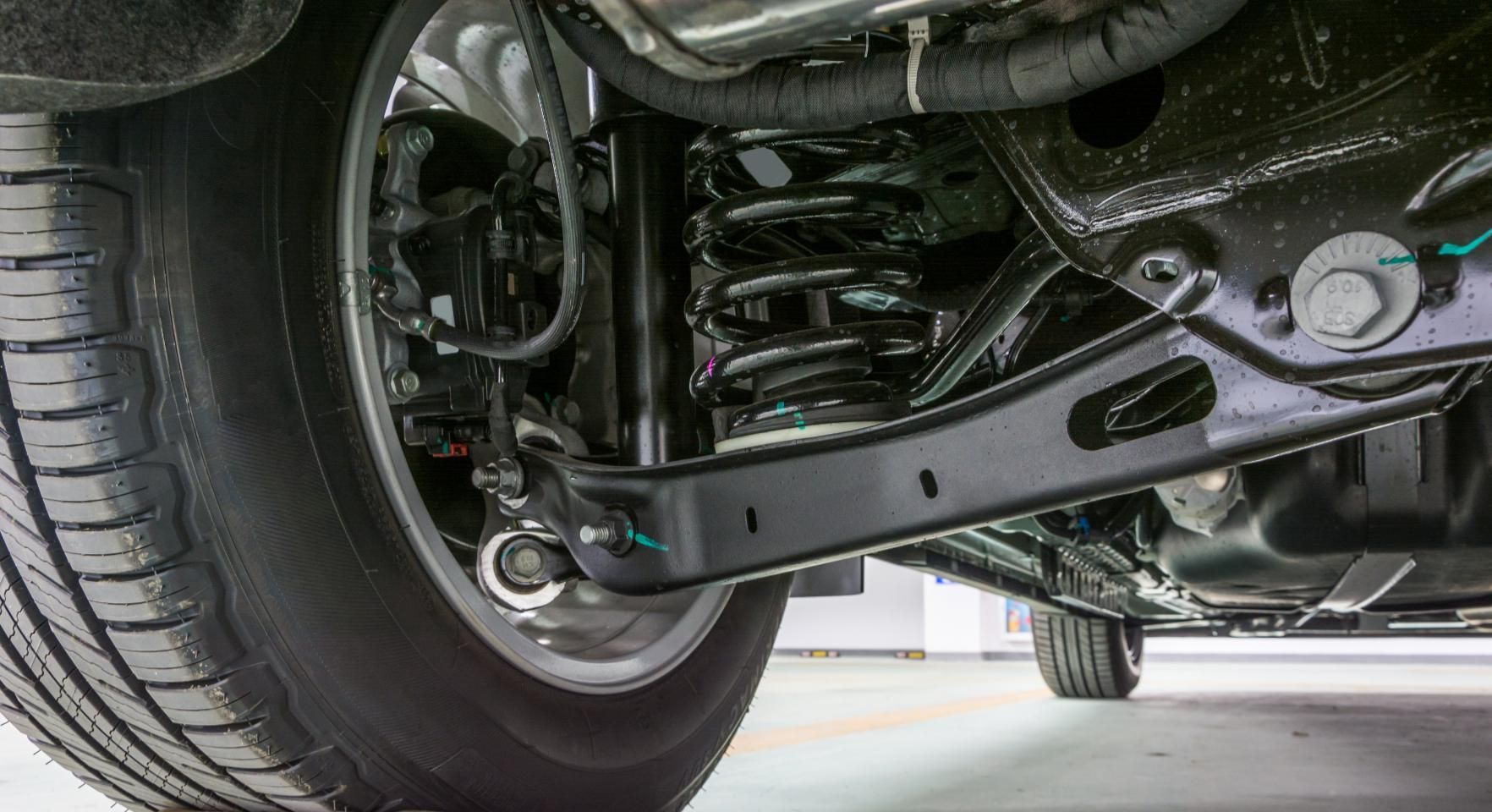 A close up of the underside of a car with a tire and suspension.