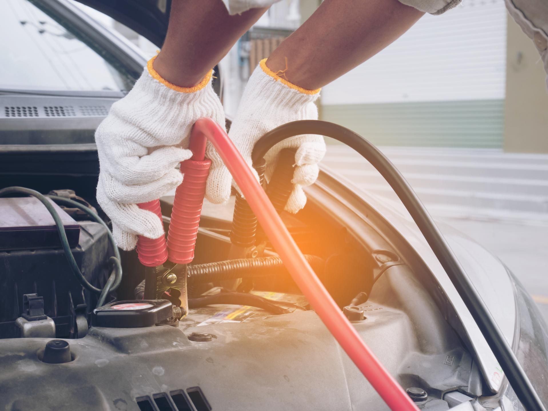 A person is charging a car battery with a jump starter.