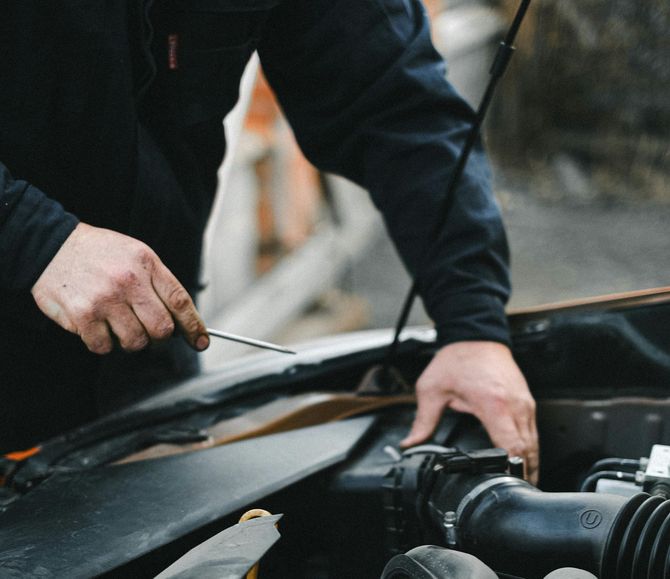Person using a wrench to work on a car engine in an open hood bay
