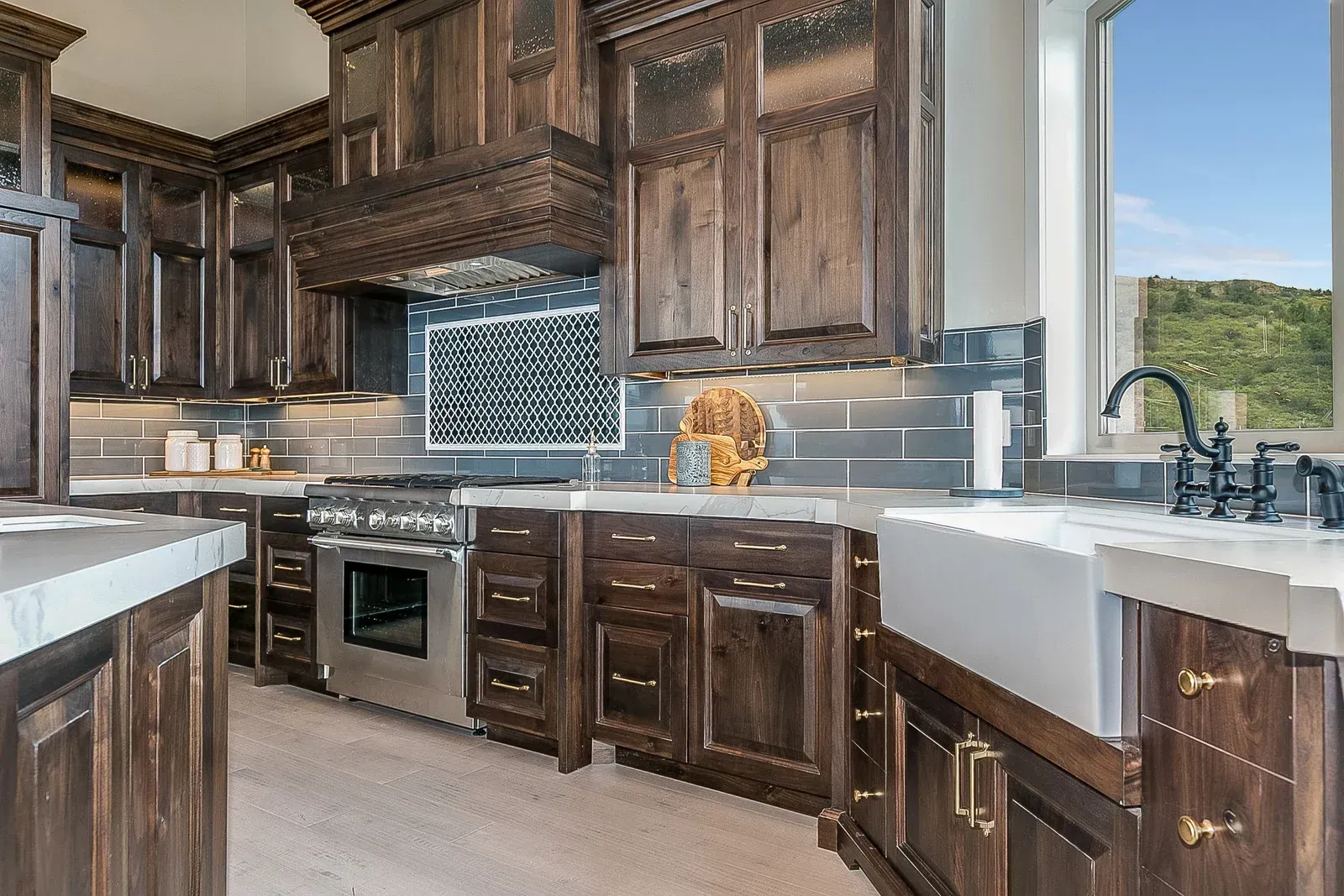 Dark wood kitchen with stainless steel appliances, white countertops, and a view.