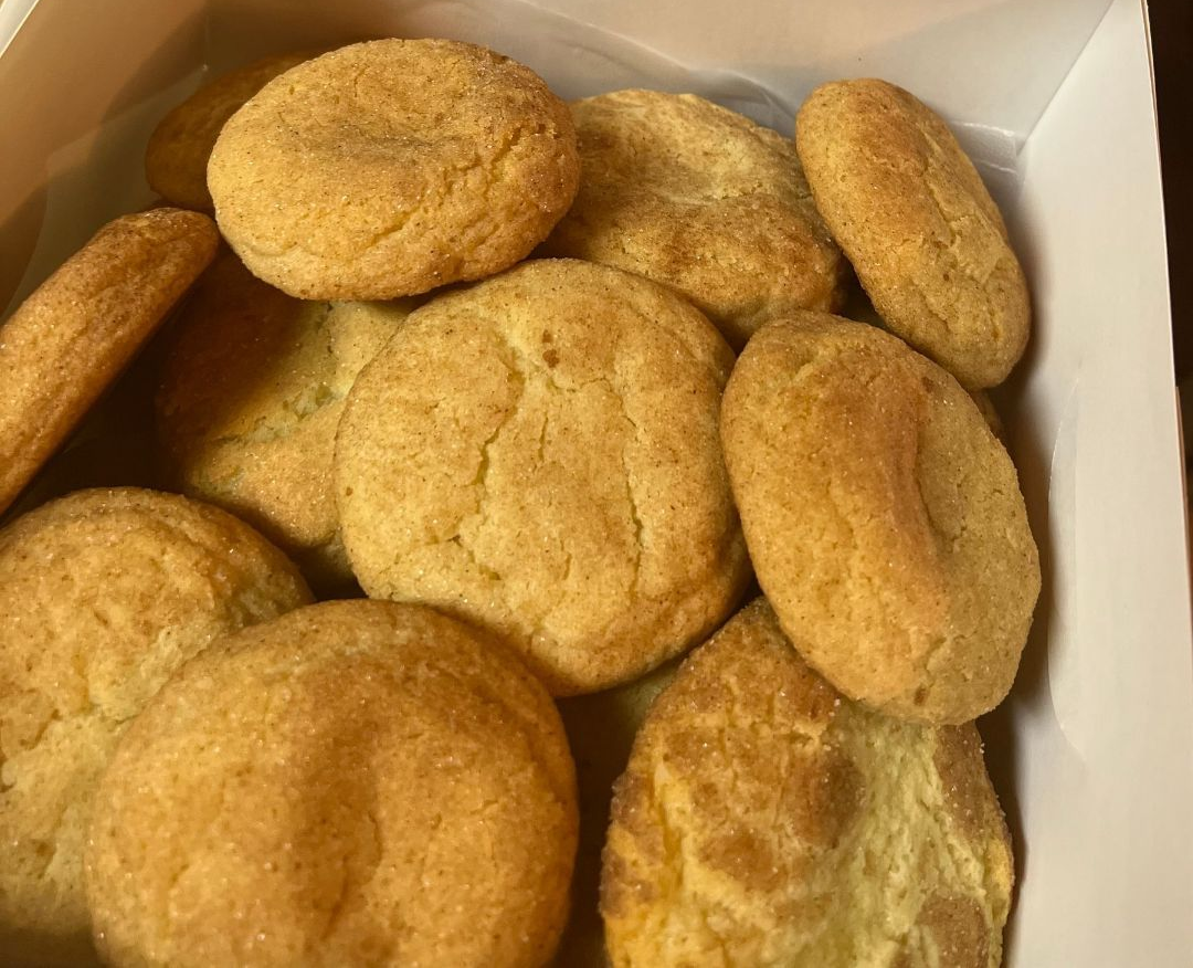 A box of golden-brown cookies, some round and some oval, stacked closely together.