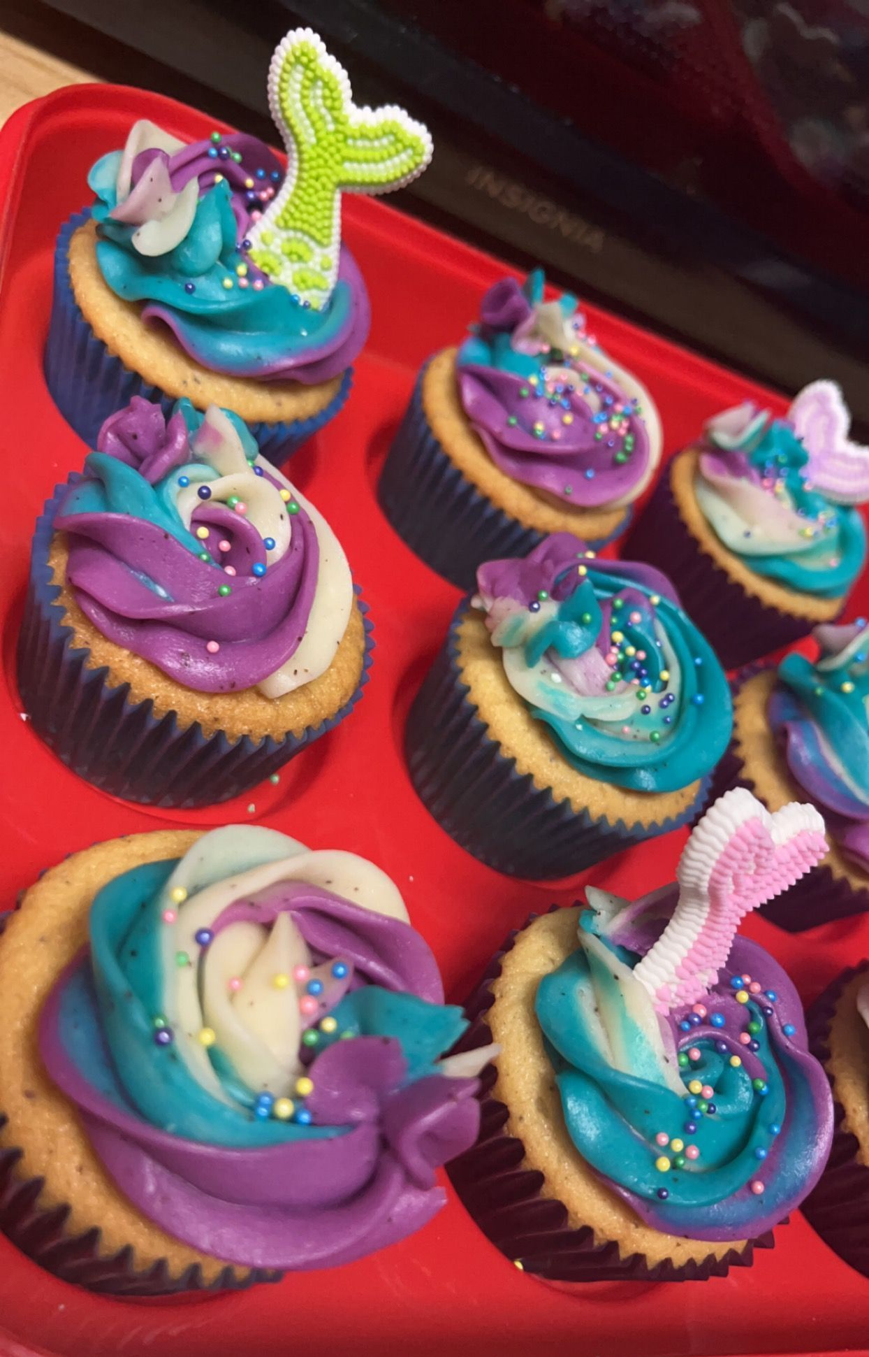 Assorted cupcakes with colorful swirled frosting and sprinkles on a red tray