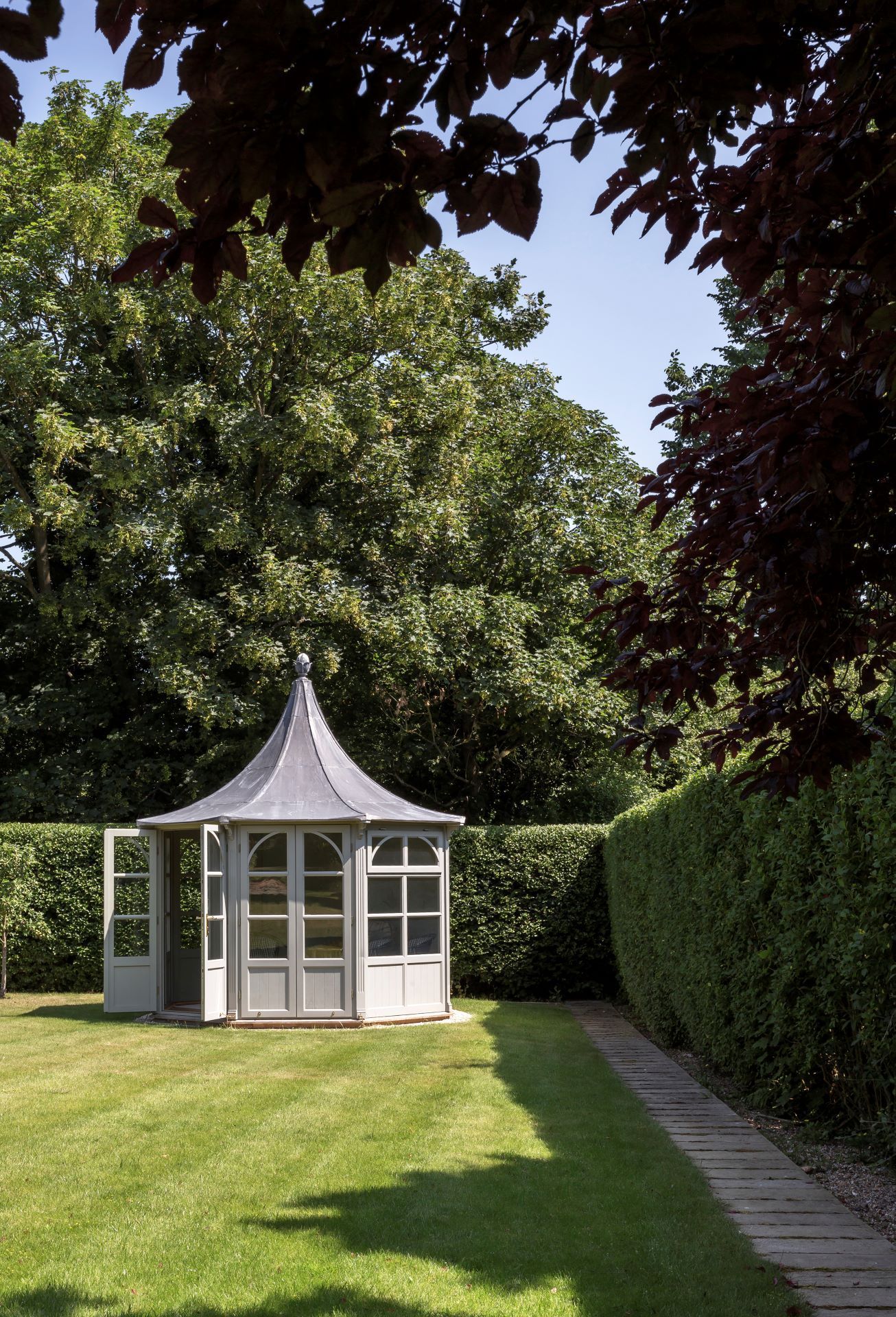 gazebo in corner of freshly mowed backyard with a wall of hedges