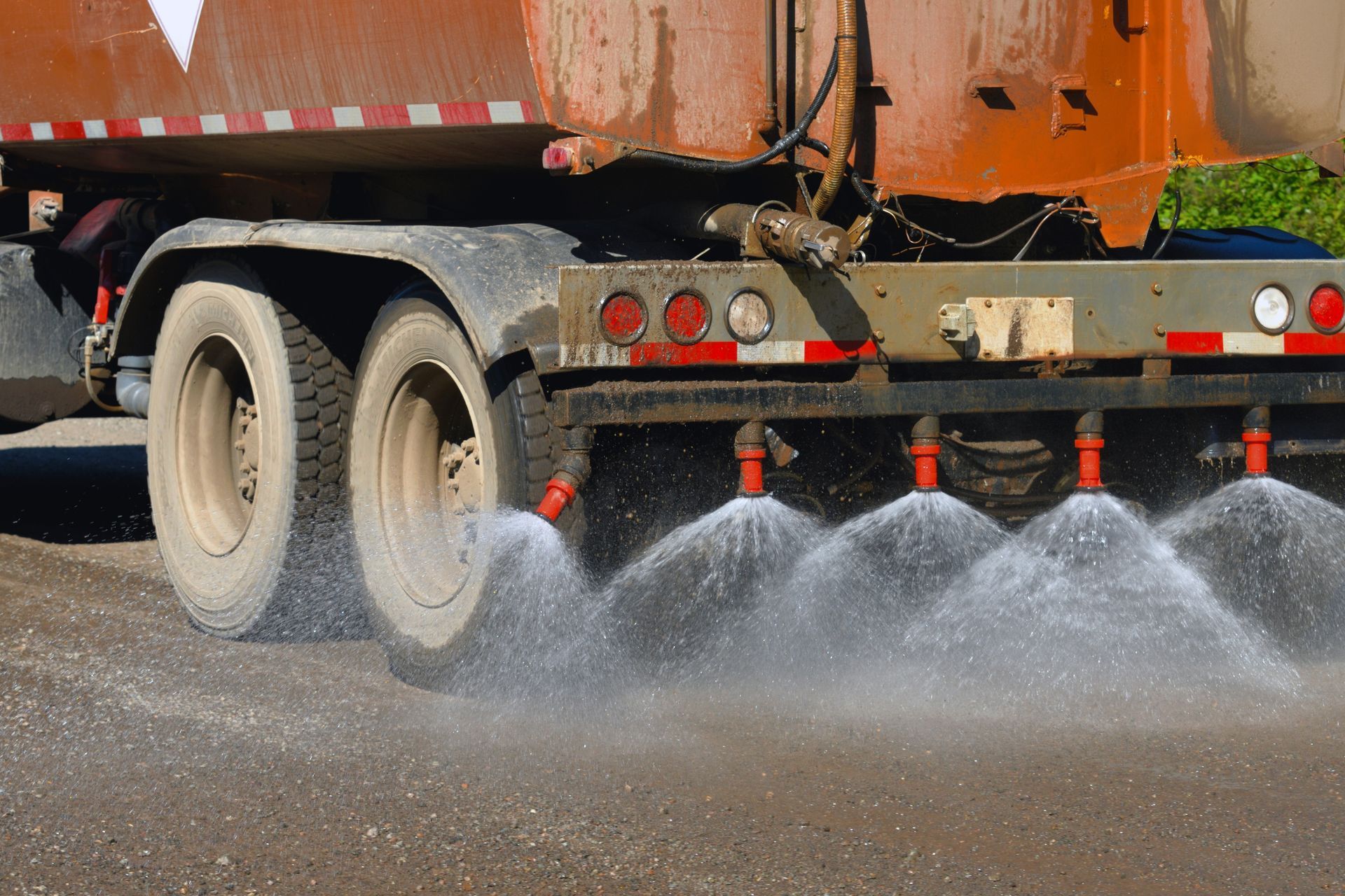 A truck is spraying water on a gravel road