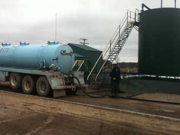 A man is standing next to a tanker truck (pump truck).