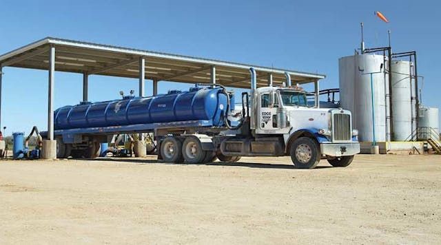 A tanker truck (pump truck) is parked in a dirt field